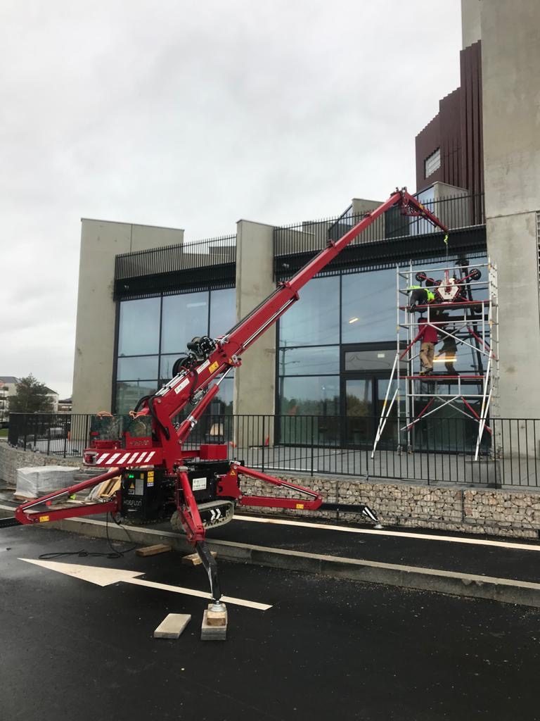 Mini-grue araignée en action devant une façade